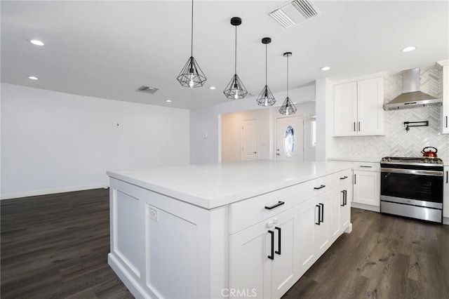 kitchen with white cabinets, wall chimney range hood, stainless steel range oven, and decorative light fixtures