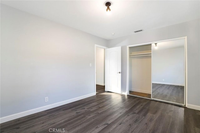 unfurnished bedroom with dark wood-type flooring and a closet