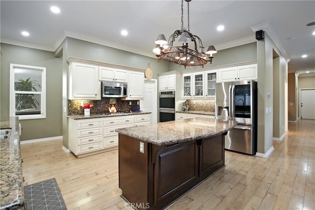 kitchen with a center island, stainless steel appliances, decorative light fixtures, and light stone countertops