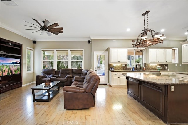 living room featuring sink, light hardwood / wood-style flooring, ornamental molding, and ceiling fan