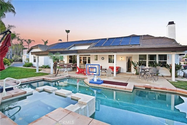 pool at dusk with exterior bar, a patio, and an in ground hot tub