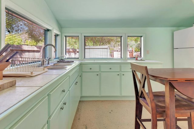 kitchen featuring lofted ceiling, sink, and green cabinetry