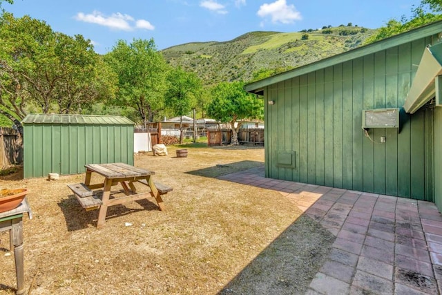 view of yard featuring a patio, a mountain view, and a shed