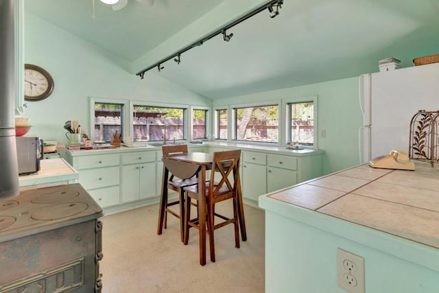 kitchen with rail lighting, sink, tile countertops, vaulted ceiling, and white refrigerator