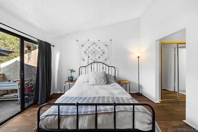 bedroom with vaulted ceiling, dark hardwood / wood-style floors, access to exterior, and a textured ceiling