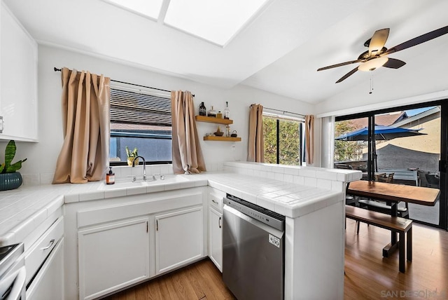 kitchen featuring white cabinetry, tile counters, stainless steel dishwasher, and kitchen peninsula