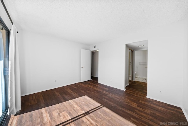 unfurnished bedroom with dark wood-type flooring and a textured ceiling