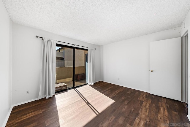 unfurnished room with dark wood-type flooring and a textured ceiling