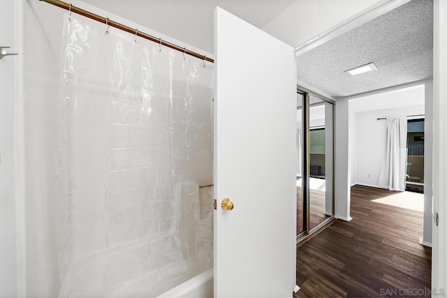 bathroom with shower / bathtub combination with curtain, wood-type flooring, floor to ceiling windows, and a textured ceiling