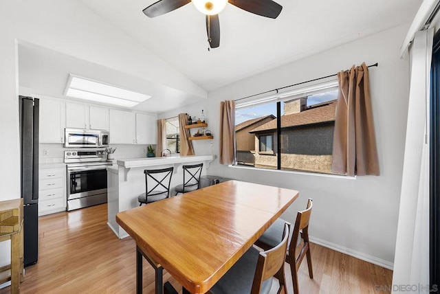 dining area with ceiling fan, lofted ceiling, and light hardwood / wood-style flooring