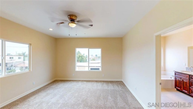 spare room with sink, light colored carpet, and ceiling fan