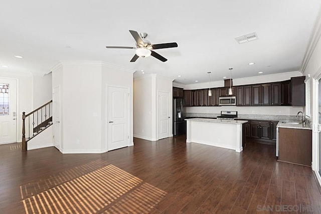 kitchen with crown molding, dark wood-type flooring, hanging light fixtures, stainless steel appliances, and a center island