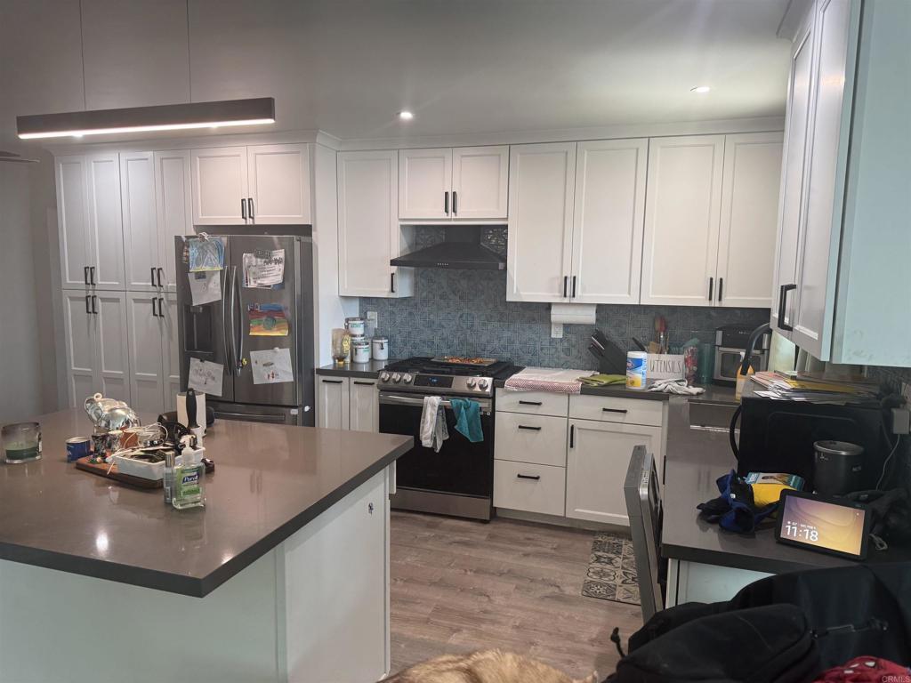 kitchen featuring white cabinetry, stainless steel appliances, decorative backsplash, and light wood-type flooring