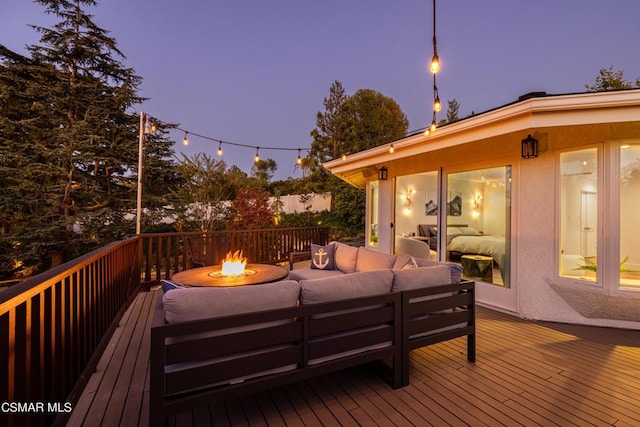 deck at dusk with an outdoor living space with a fire pit