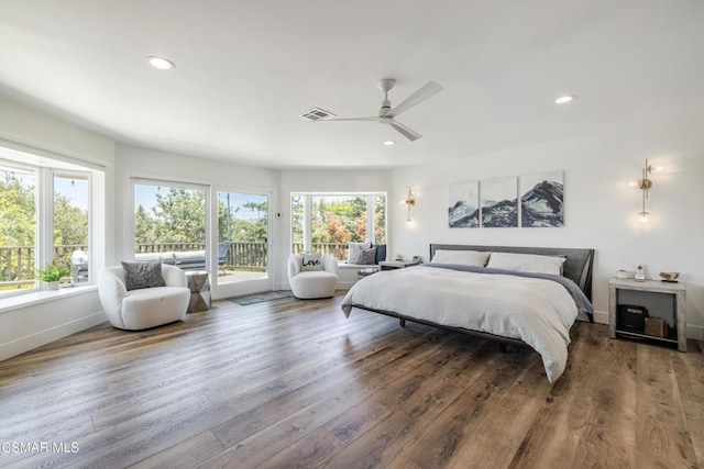 bedroom with multiple windows, wood-type flooring, and access to exterior