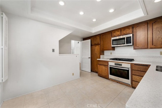 kitchen featuring crown molding, a tray ceiling, light tile patterned flooring, and appliances with stainless steel finishes