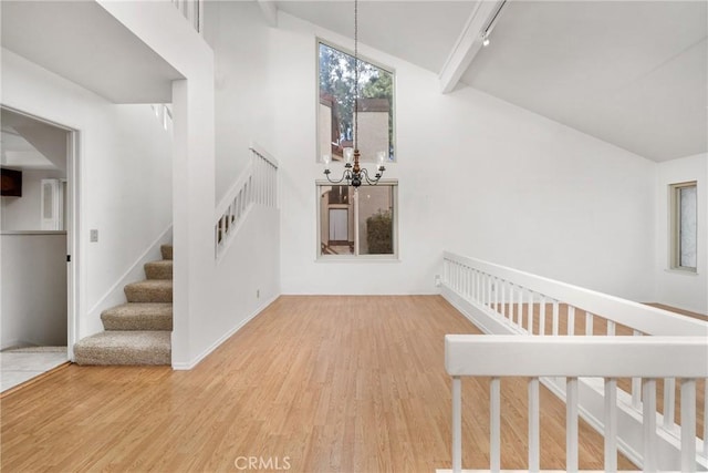 staircase featuring hardwood / wood-style flooring, high vaulted ceiling, and a chandelier