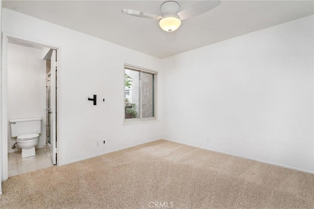 unfurnished bedroom with ceiling fan, ensuite bath, and light carpet