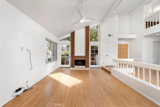 unfurnished living room featuring a brick fireplace, high vaulted ceiling, ceiling fan, and light hardwood / wood-style flooring