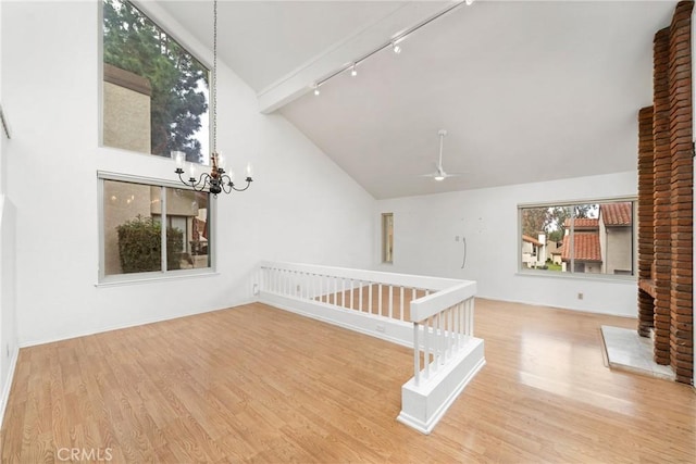 interior space featuring ceiling fan with notable chandelier, a healthy amount of sunlight, rail lighting, and light hardwood / wood-style floors