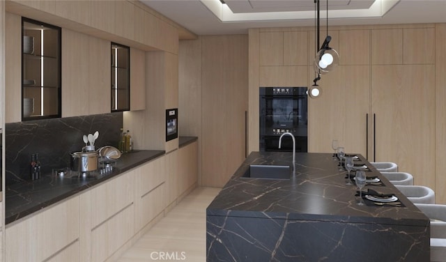 kitchen featuring light brown cabinetry, sink, a raised ceiling, double oven, and backsplash