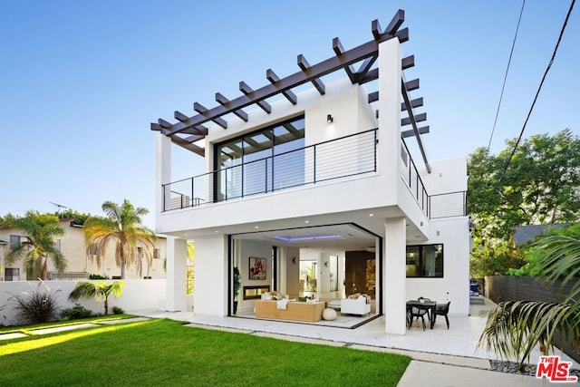 back of house with a balcony, outdoor lounge area, a yard, and a patio area