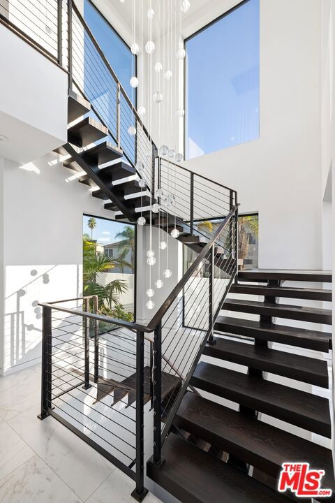 stairs featuring an inviting chandelier, a wealth of natural light, and a high ceiling