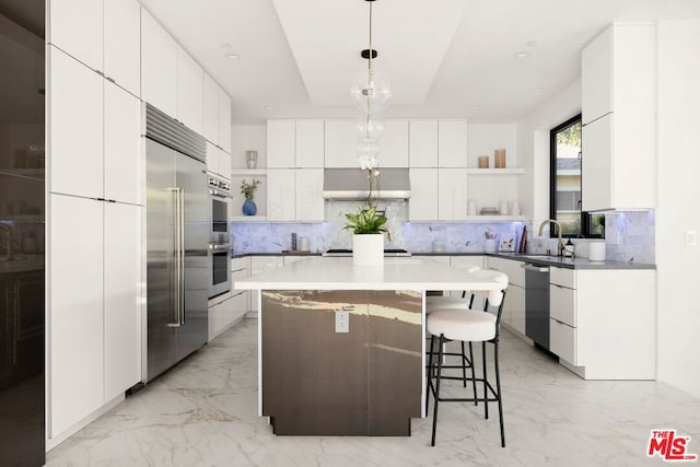 kitchen featuring a kitchen island, white cabinetry, sink, hanging light fixtures, and stainless steel appliances