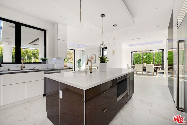 kitchen featuring stainless steel appliances, white cabinetry, sink, and a center island with sink