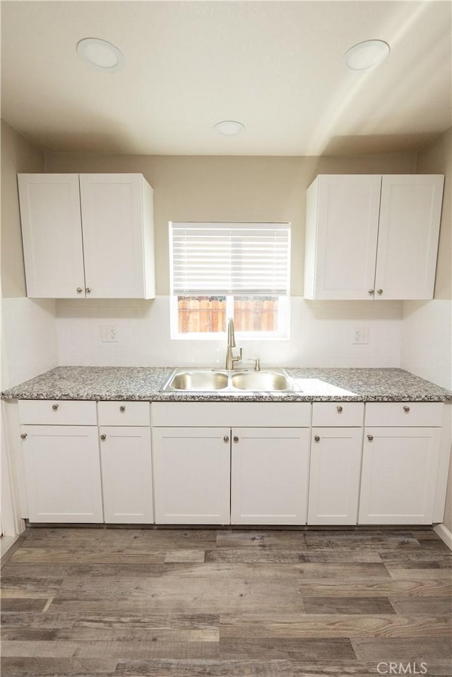 kitchen featuring sink, light stone counters, white cabinets, and dark hardwood / wood-style flooring