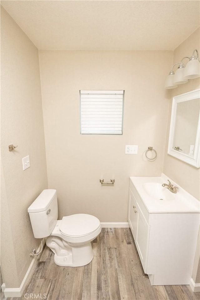 bathroom featuring wood-type flooring, vanity, and toilet