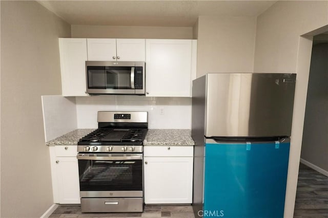 kitchen with light stone countertops, white cabinetry, and appliances with stainless steel finishes