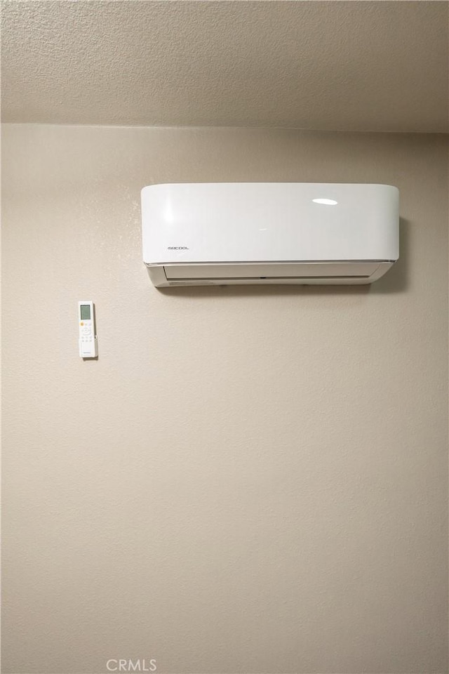 interior details with a wall mounted air conditioner and a textured ceiling