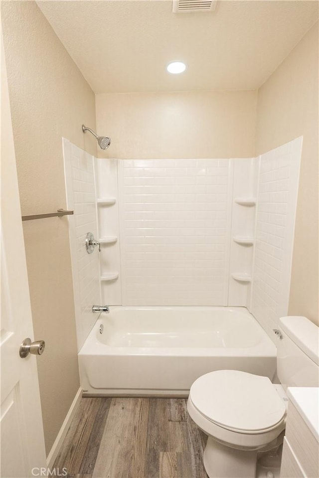 bathroom with toilet, bathing tub / shower combination, and hardwood / wood-style floors