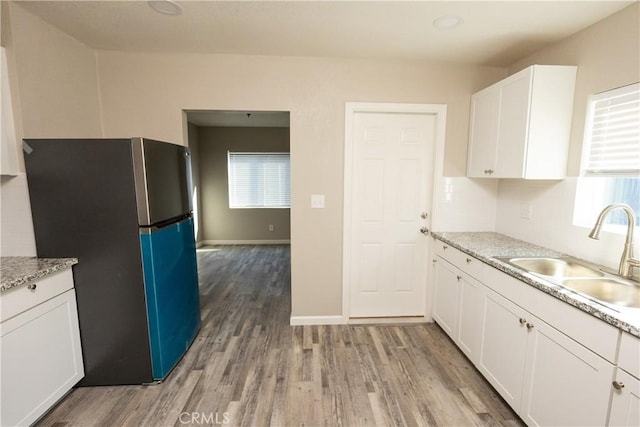 kitchen featuring stainless steel refrigerator, white cabinetry, light hardwood / wood-style floors, and sink