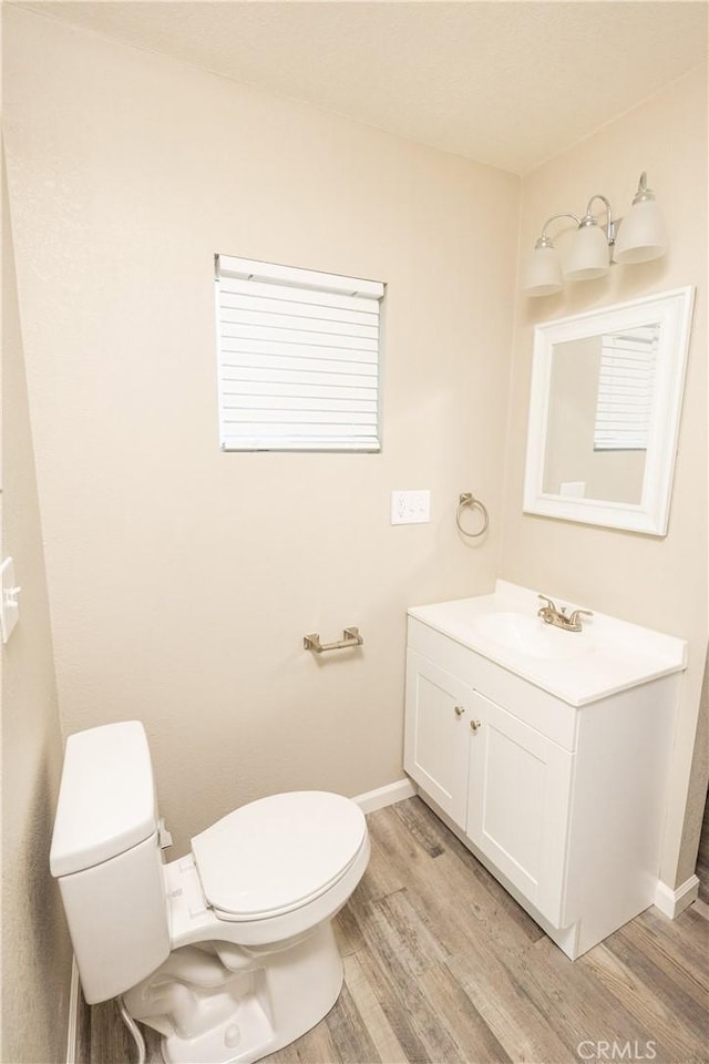 bathroom with wood-type flooring, vanity, and toilet