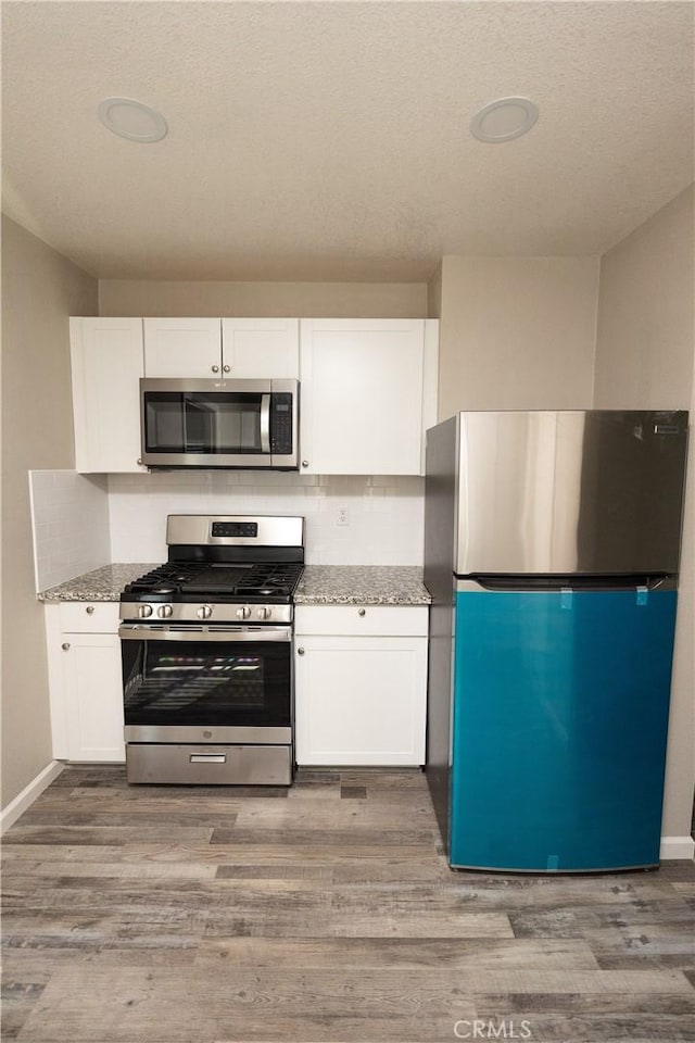 kitchen featuring light stone counters, stainless steel appliances, and white cabinets