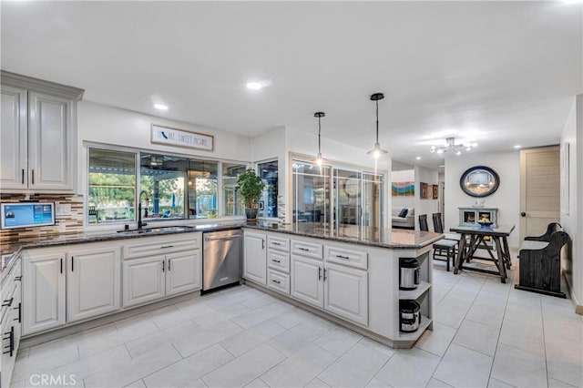 kitchen featuring tasteful backsplash, sink, hanging light fixtures, stainless steel dishwasher, and kitchen peninsula