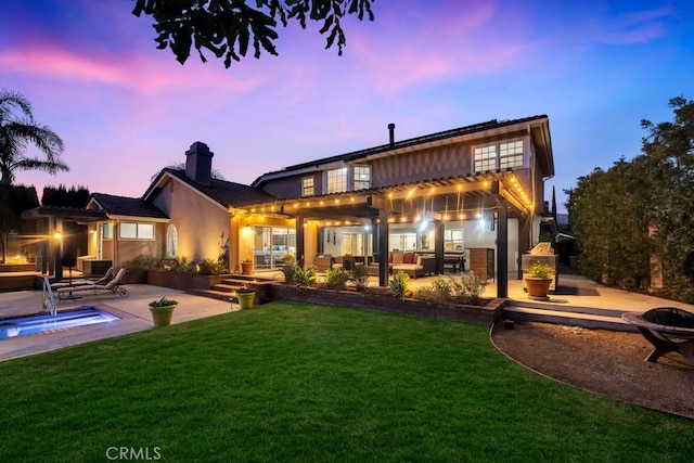 back house at dusk with an outdoor living space, a patio area, and a lawn