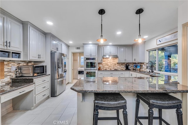 kitchen with sink, decorative light fixtures, dark stone counters, and appliances with stainless steel finishes