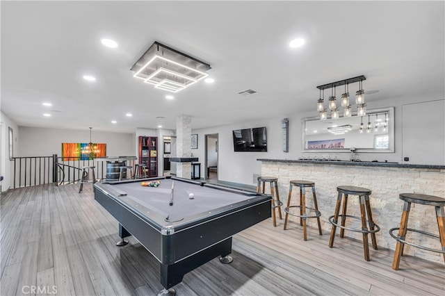 game room with bar, pool table, and light hardwood / wood-style flooring