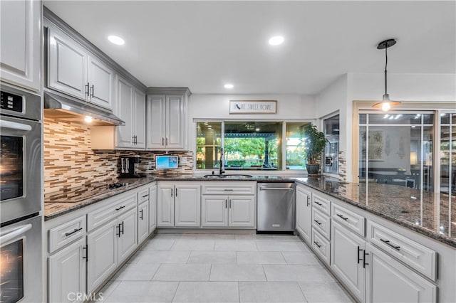 kitchen featuring appliances with stainless steel finishes, pendant lighting, sink, dark stone countertops, and backsplash