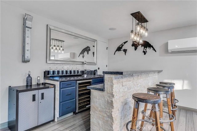 bar featuring wine cooler, blue cabinets, decorative light fixtures, light wood-type flooring, and a wall unit AC