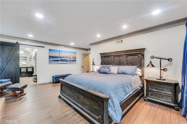 bedroom featuring crown molding, wood-type flooring, and a barn door