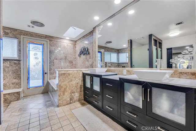 bathroom featuring vanity, a skylight, tile walls, and a wealth of natural light