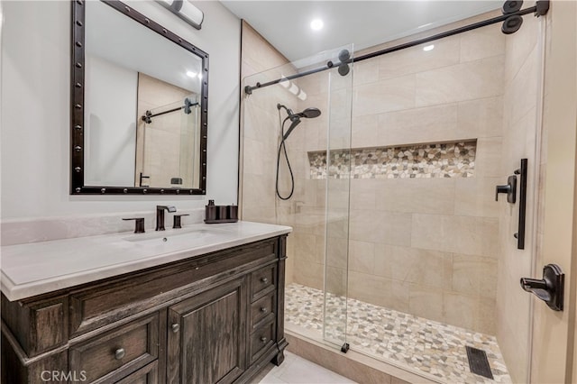 bathroom with a shower with door, vanity, and tile patterned flooring