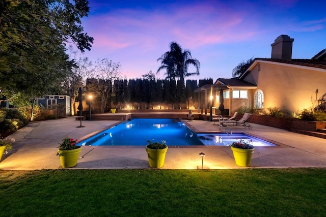 pool at dusk featuring a yard and a patio