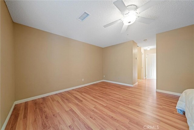 empty room with ceiling fan, a textured ceiling, and light wood-type flooring