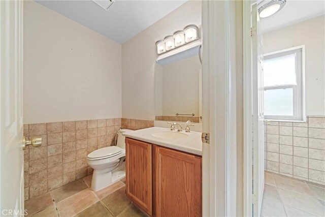 bathroom with tile walls, vanity, tile patterned floors, and toilet