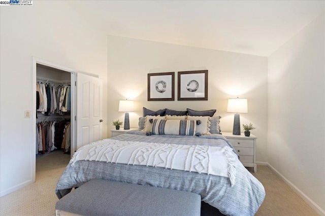 bedroom featuring a walk in closet, lofted ceiling, light carpet, and a closet